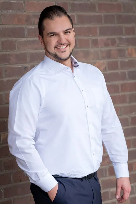 Junger Mann im weißen Hemd lächelt freundlich in die Kamera.