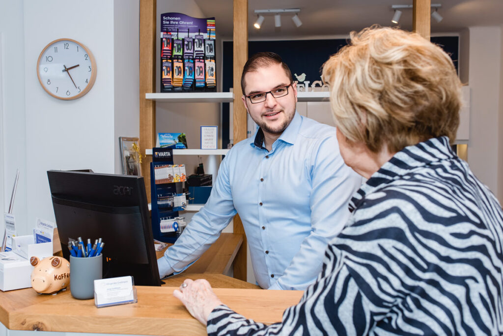 Beratungsgespräch mit Blick auf Kundin und Mitarbeiter am Tresen.