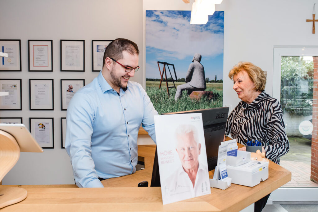 Freundliches Gespräch zwischen Mitarbeiter und Kundin im Empfangsbereich.