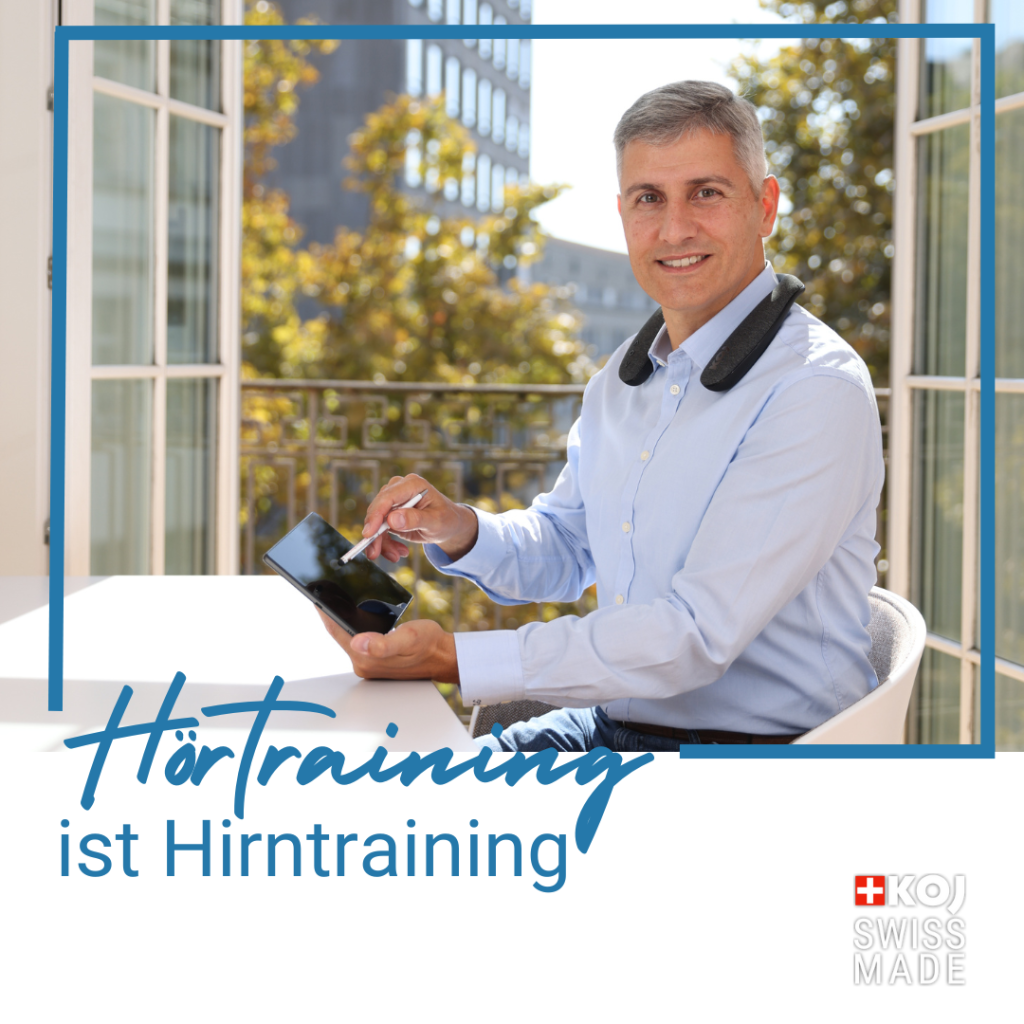 Auf derm Bild ist ein Mann im Anzug zu sehen der in die Kamera lächelt und ein Tablet in der Hand hält, während unten links der Text "Hörtraining ist Hirntraining" zu lesen ist.