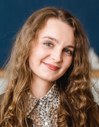 Eine junge Frau mit gewellten Haaren lächelt freundlich in die Kamera.